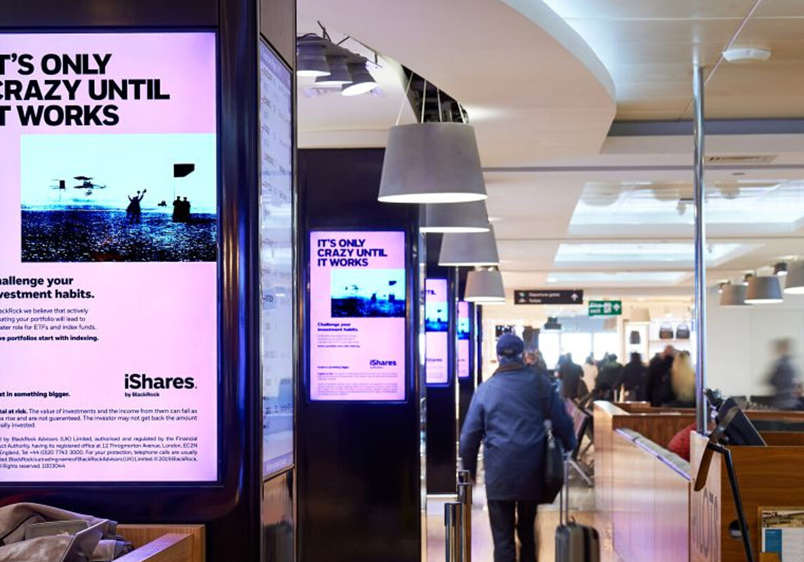 DOOH screens inside an airport terminal displaying targeted ads to travelers.